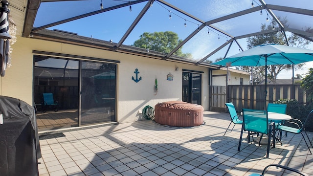 view of patio / terrace featuring glass enclosure and a hot tub