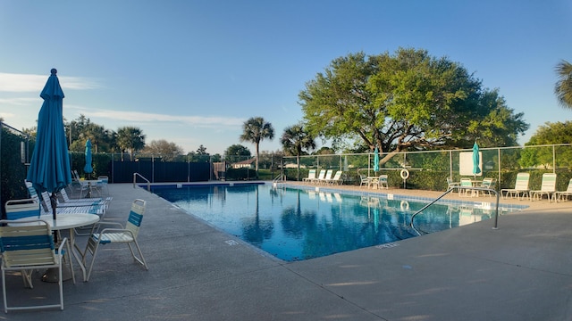 pool with a patio area and fence