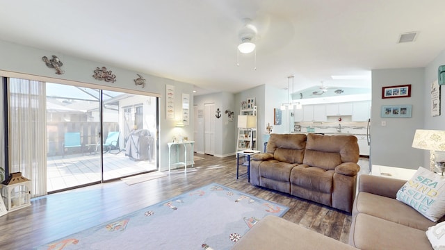 living room with lofted ceiling, visible vents, ceiling fan, wood finished floors, and baseboards