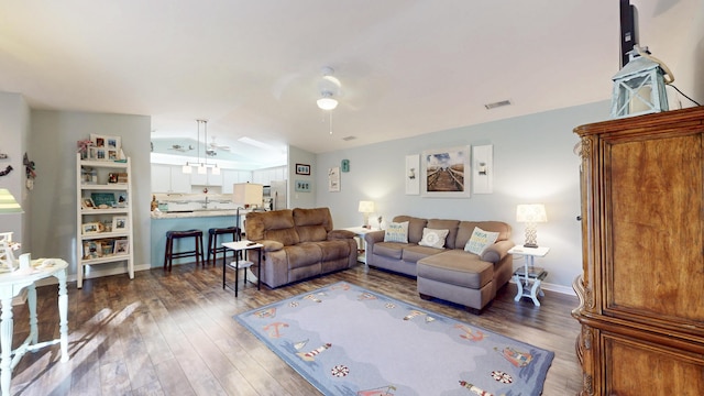 living area with lofted ceiling, visible vents, a ceiling fan, wood finished floors, and baseboards