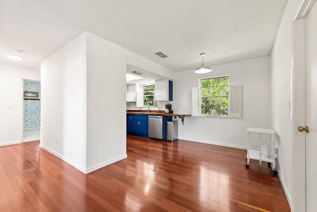 kitchen featuring blue cabinetry, butcher block counters, visible vents, stainless steel dishwasher, and a sink