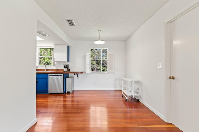 kitchen with visible vents, dishwasher, hardwood / wood-style flooring, blue cabinetry, and a sink