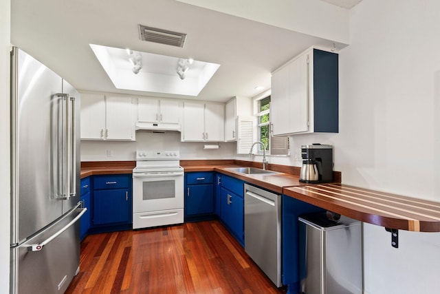 kitchen featuring under cabinet range hood, blue cabinets, stainless steel appliances, butcher block countertops, and a sink