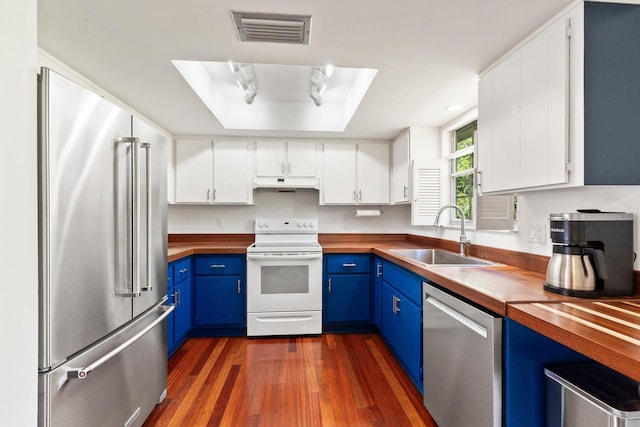 kitchen featuring appliances with stainless steel finishes, a sink, wood counters, and blue cabinets