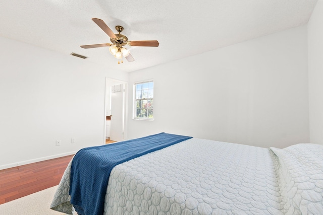 bedroom with visible vents, ceiling fan, a textured ceiling, wood finished floors, and baseboards