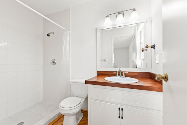 full bathroom featuring toilet, tiled shower, and vanity