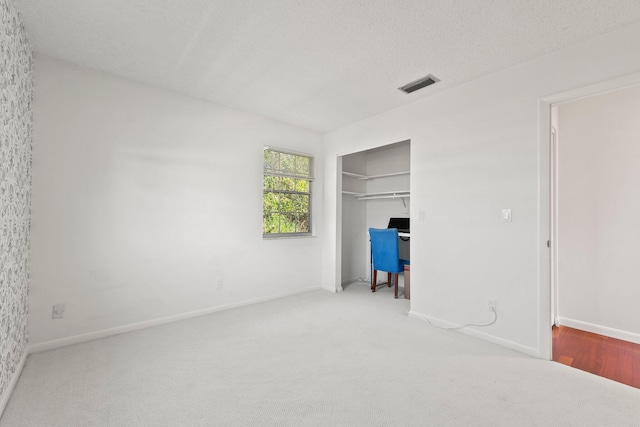 unfurnished bedroom with carpet floors, a closet, visible vents, a textured ceiling, and baseboards