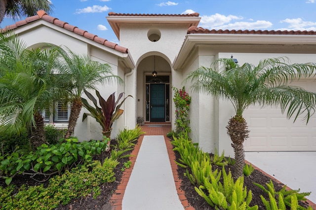 entrance to property with a garage and stucco siding