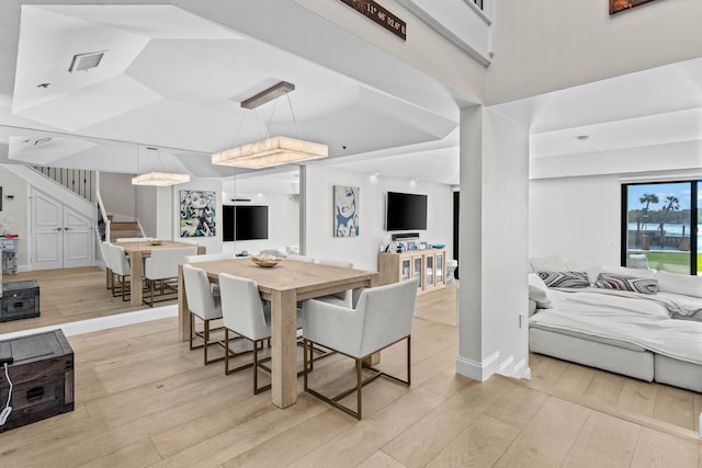 dining room with light wood-style floors, visible vents, baseboards, and stairs