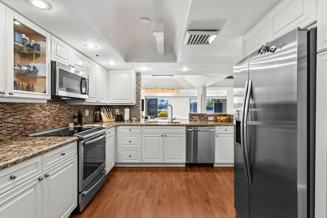 kitchen with appliances with stainless steel finishes, dark wood finished floors, white cabinets, and a sink