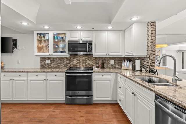 kitchen with tasteful backsplash, light wood-style flooring, stainless steel appliances, white cabinetry, and a sink