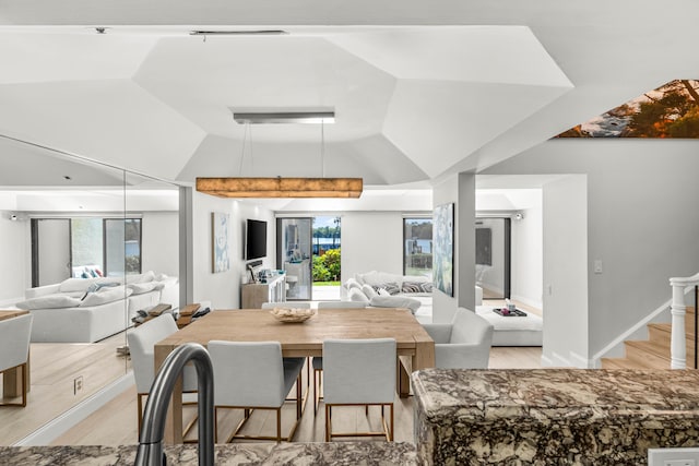 dining area with lofted ceiling, stairway, and light wood finished floors