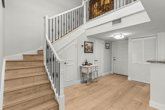 staircase with baseboards, visible vents, and hardwood / wood-style floors