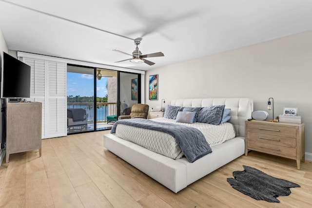 bedroom with access to exterior, light wood-style flooring, expansive windows, and ceiling fan