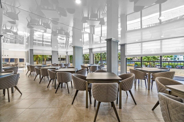 dining space featuring light tile patterned flooring, a towering ceiling, and a wealth of natural light