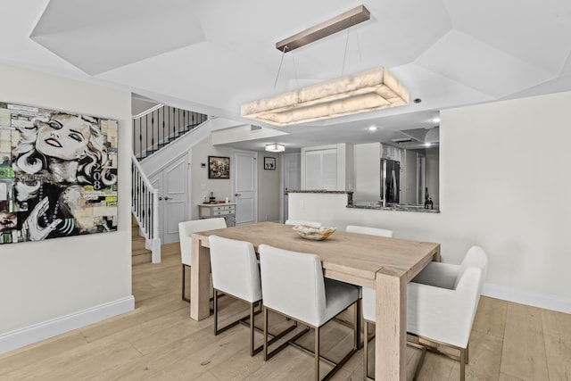 dining space with baseboards, vaulted ceiling, stairway, and light wood finished floors