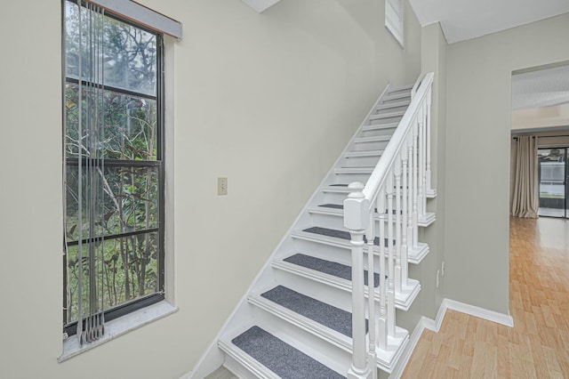 stairway with baseboards and wood finished floors