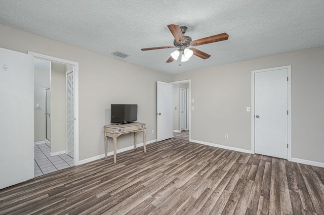 interior space with a textured ceiling, visible vents, and wood finished floors