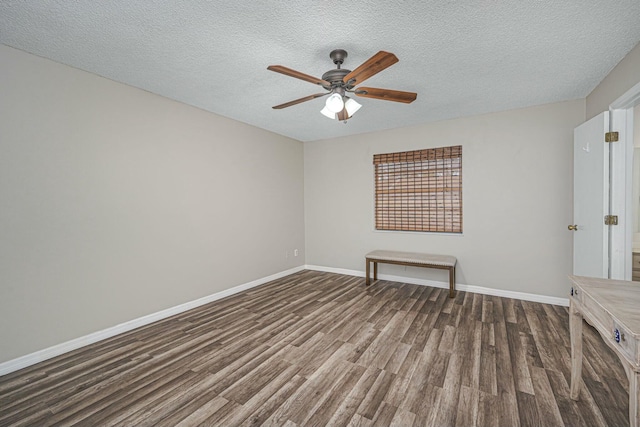 empty room featuring dark wood-style flooring, ceiling fan, a textured ceiling, and baseboards