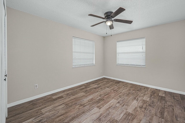 empty room featuring a textured ceiling, wood finished floors, a ceiling fan, and baseboards