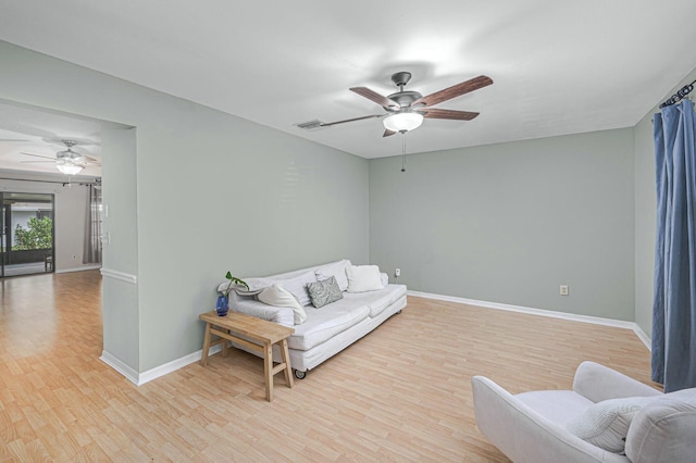 living room with a ceiling fan, visible vents, baseboards, and wood finished floors