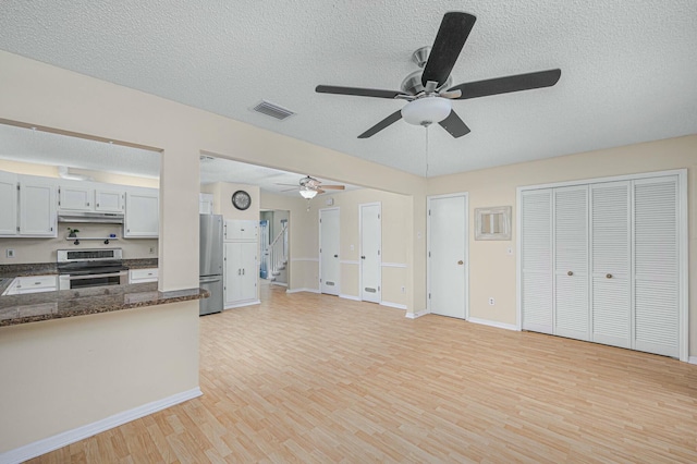 kitchen featuring a textured ceiling, under cabinet range hood, stainless steel appliances, visible vents, and light wood finished floors