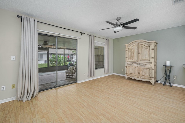 spare room with visible vents, a ceiling fan, a textured ceiling, light wood-type flooring, and baseboards