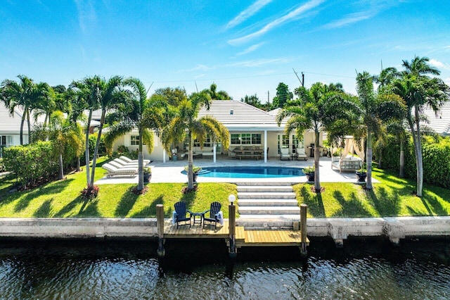 back of house featuring outdoor lounge area, a patio, a lawn, and a water view