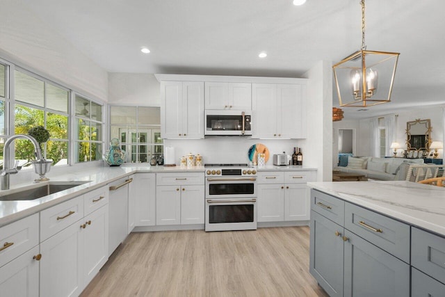 kitchen with white appliances, light stone counters, gray cabinets, a sink, and light wood-type flooring