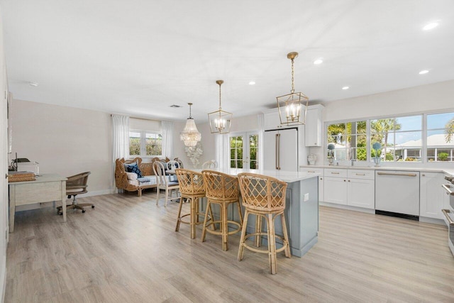 kitchen with a breakfast bar area, light countertops, dishwasher, high quality fridge, and a center island