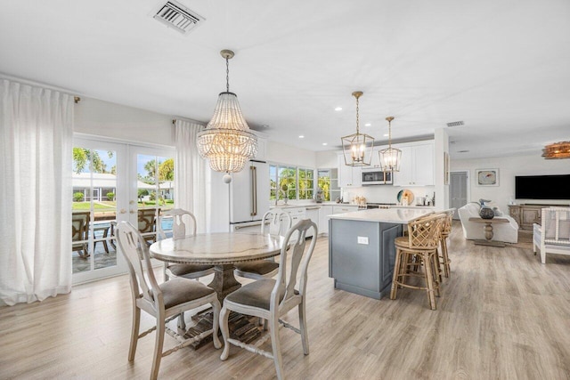 dining area with plenty of natural light, light wood-style floors, visible vents, and a chandelier