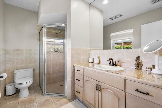 bathroom featuring vanity, visible vents, a shower stall, tile walls, and toilet