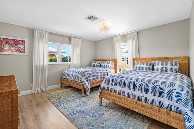 bedroom featuring multiple windows, wood finished floors, visible vents, and baseboards