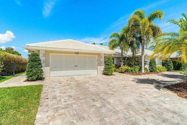 single story home with fence, a tiled roof, stucco siding, decorative driveway, and a garage