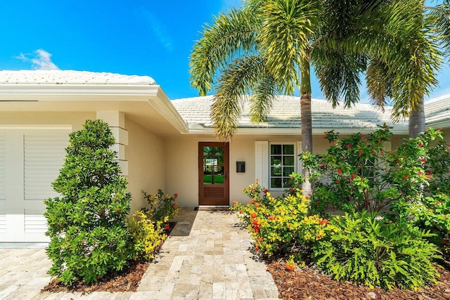 entrance to property featuring a garage and stucco siding