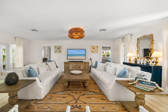 living area with visible vents, a healthy amount of sunlight, and wood finished floors