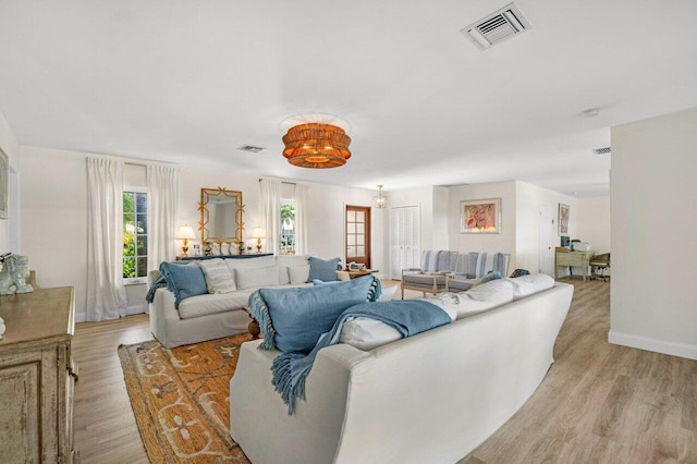 living room with light wood-style floors, visible vents, and baseboards