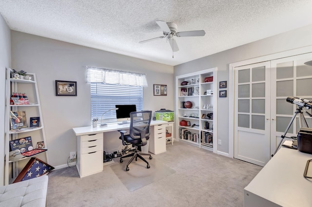 office space with baseboards, ceiling fan, light carpet, and a textured ceiling