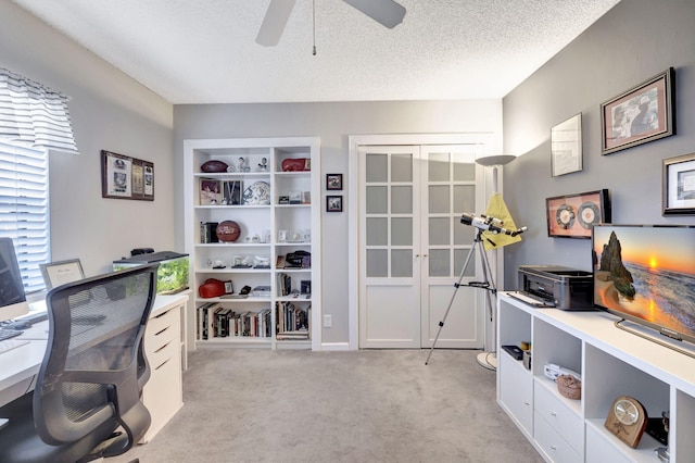 office area with a ceiling fan, a textured ceiling, and light colored carpet