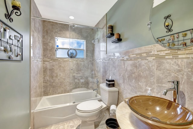 full bathroom featuring a sink, tile walls, combined bath / shower with glass door, and toilet