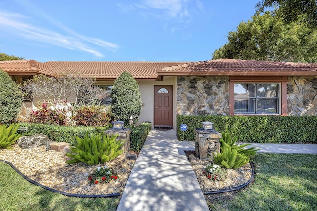 view of front of property with a tile roof, stone siding, and stucco siding