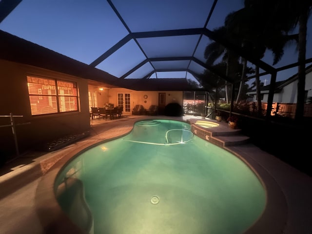 pool at twilight with a lanai, a patio, and a pool with connected hot tub