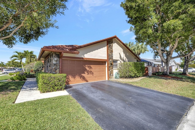 view of front facade featuring a garage, a front yard, stucco siding, driveway, and a tile roof