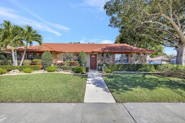 view of front of house featuring a tile roof, a front yard, stone siding, and stucco siding