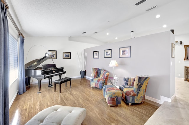 living area with recessed lighting, visible vents, wood finished floors, and lofted ceiling