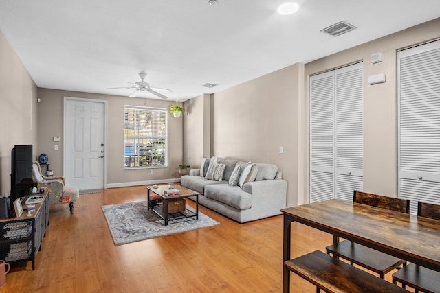 living area featuring light wood finished floors, baseboards, visible vents, and a ceiling fan