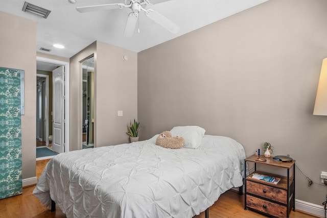 bedroom with wood finished floors, visible vents, and baseboards