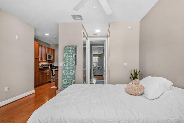 bedroom featuring baseboards, visible vents, ceiling fan, and wood finished floors