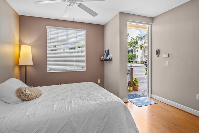 bedroom with access to exterior, a ceiling fan, baseboards, and wood finished floors