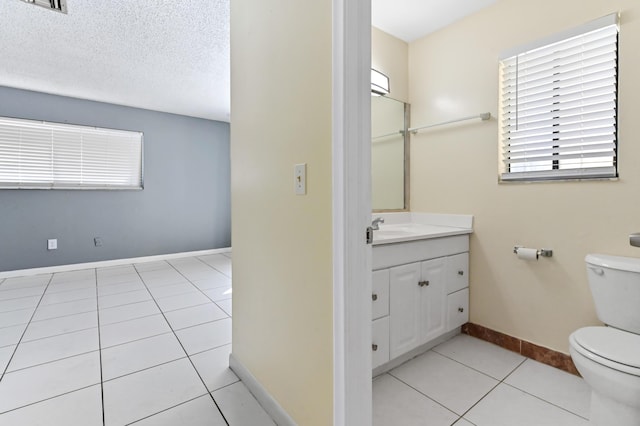 bathroom with tile patterned flooring, baseboards, toilet, vanity, and a textured ceiling